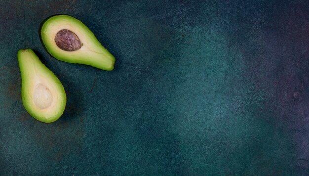 Kopierraum der Draufsicht halbierte Avocado auf einem dunkelgrünen Hintergrund