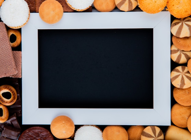 Kopierraum der Draufsicht mischen Kekse mit Marshmallows und einem weißen Rahmen mit einem schwarzen Hintergrund