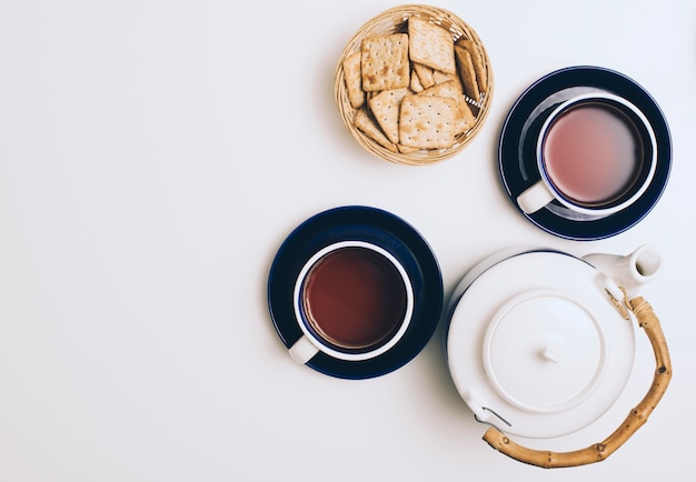 Korb mit Crackern; Tasse Kaffee und Teekanne auf weißem Hintergrund
