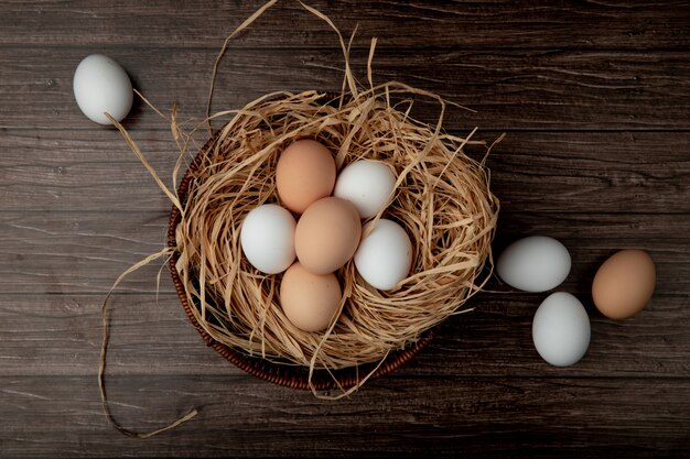 Korb mit Eiern im Nest mit Eiern auf Holztisch