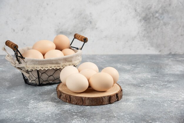 Korb mit frischen, ungekochten Bio-Eiern auf Marmoroberfläche.