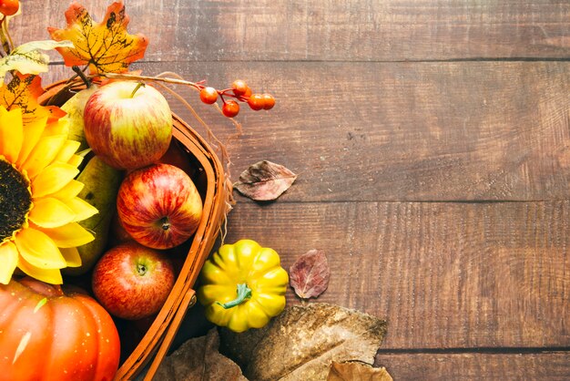 Korb mit herbstlicher Ernte und Sonnenblume auf Tabelle