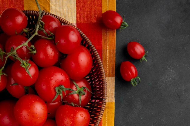 Korb mit Tomaten auf der linken Seite auf schwarzer Oberfläche