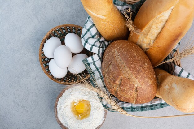 Korb mit verschiedenen Broten zusammen mit Mehl und Eiern. Hochwertiges Foto