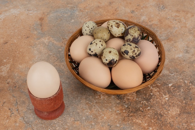 Korb mit weißen Eiern auf Marmortisch.
