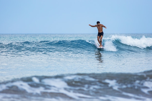 Koreanischer Surfer reitet ein Longboard auf blauen Wellen