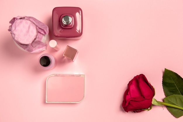 Kosmetik, Parfüm und Rose. Monochrome stilvolle und trendige Komposition in rosa Farbe an der Studiowand. Ansicht von oben, flach.