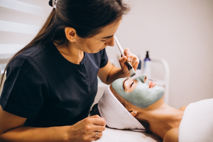 Kostenlose Foto kosmetikerin, die maske auf einem gesicht des kunden in einem schönheitssalon anwendet