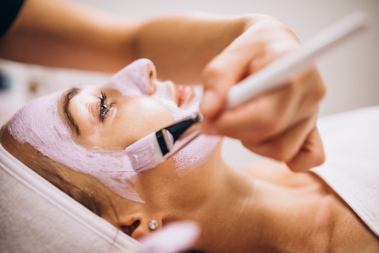 Kostenlose Foto kosmetikerin, die maske auf einem gesicht des kunden in einem schönheitssalon anwendet