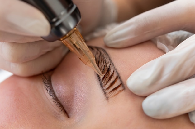 Kostenloses Foto kosmetikerin führt ein microblading-verfahren an den augenbrauen einer kundin durch