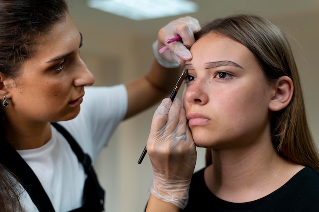 Kosmetikerin führt ein Microblading-Verfahren an einer jungen Frau durch