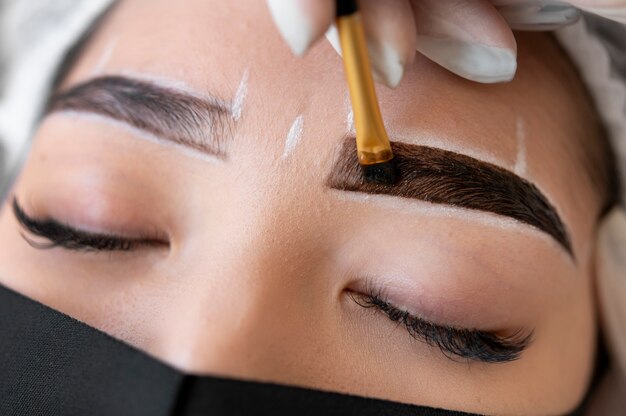 Kosmetikerin führt eine Microblading-Behandlung an den Augenbrauen einer Kundin durch