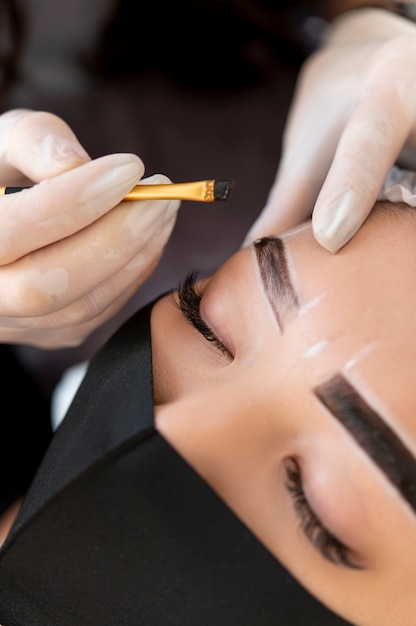 Kosmetikerin führt eine Microblading-Behandlung an den Augenbrauen einer Kundin durch