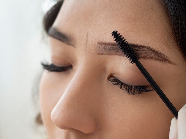 Kosmetikerin führt eine Microblading-Behandlung an den Augenbrauen einer Kundin durch