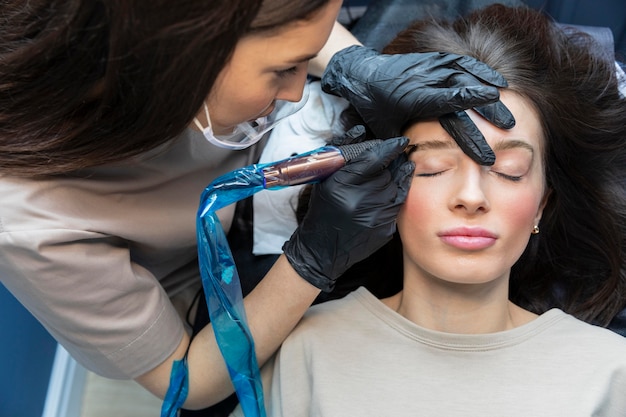 Kosmetikerin macht eine augenbrauenbehandlung für ihren klienten