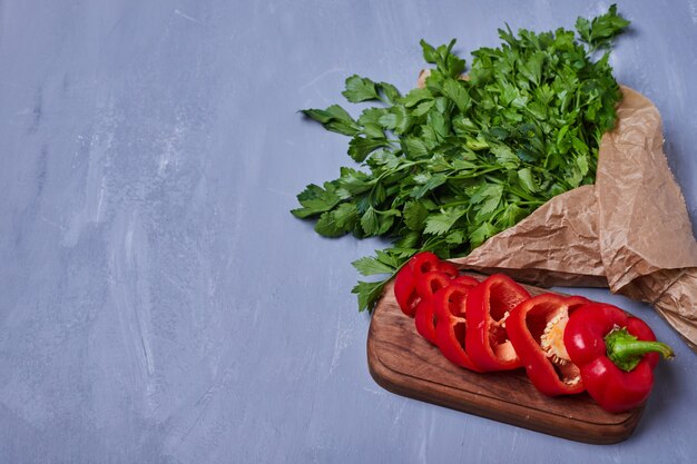 Kräuter und Chilis auf einem Holzbrett auf Blau