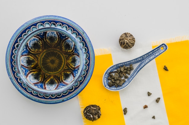 Kostenloses Foto kräutertee mit blühendem teeblumenball und oolong-teestaub gegen weißen hintergrund