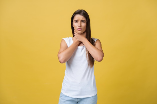 Kranke Frau, die an Halsschmerzen leidet, isoliert auf gelbem Hintergrund