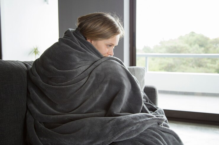 Kostenlose Foto kranke frau, die auf sofa sitzt, ihre knie umarmend und denken