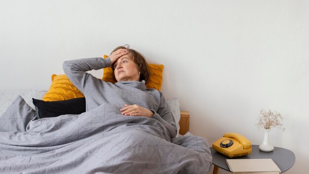 Kranke Frau mit mittlerem Schuss, die im Bett liegt