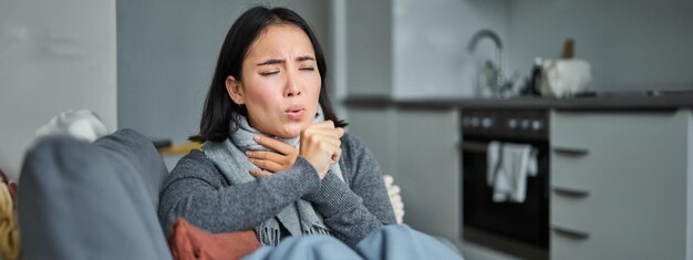 Kostenloses Foto kranke koreanische frau, die hustet und sich unwohl fühlt und eine grimasse zieht, hat grippe, erkältung oder grippe