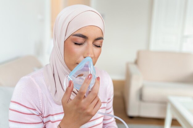 Kranke muslimische frau mit hijab auf sauerstoffmaske inhalation pneumonie coronavirus pandemie kranke frau, die eine sauerstoffmaske trägt und sich einer behandlung unterzieht covid 19