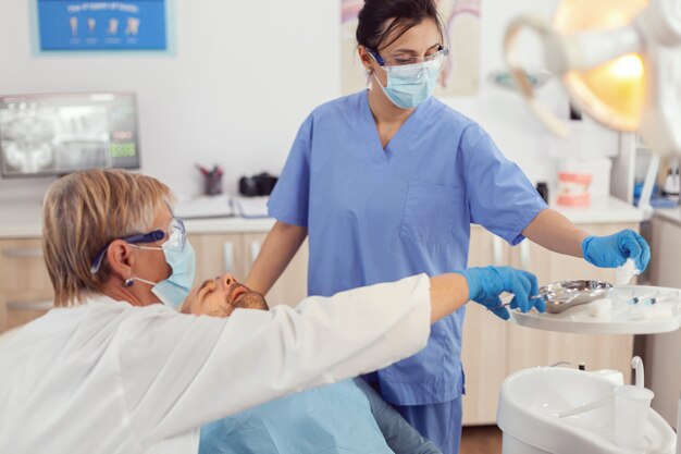 Krankenhausteam, das in der Zahnchirurgie arbeitet und die Gesundheit der Zähne mit stomatologischen Werkzeugen analysiert, die im Büro der medizinischen Klinik arbeiten
