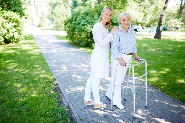 Krankenschwester älterer Frau hilft, Rollator zu benutzen