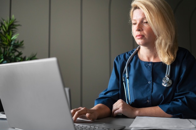 Kostenloses Foto krankenschwester der seitenansicht, die auf der tastatur tippt