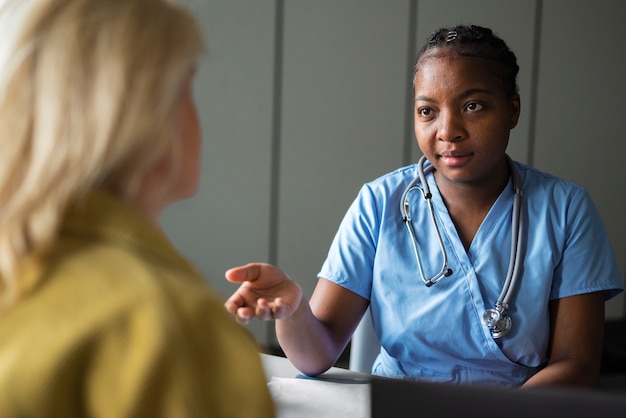 Kostenloses Foto krankenschwester der vorderansicht, die mit dem patienten spricht