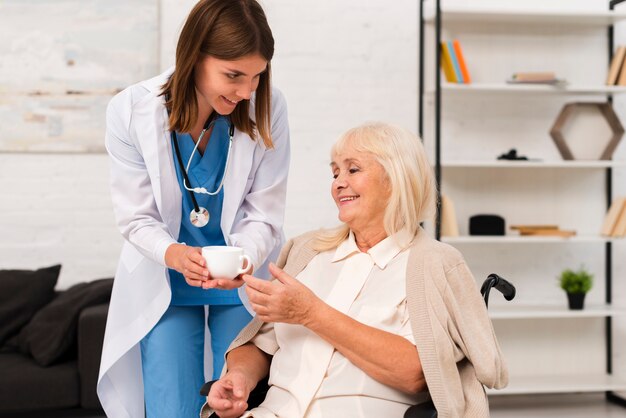 Krankenschwester, die der alten Frau Tee gibt