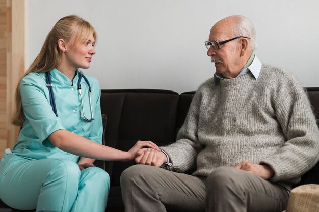 Krankenschwester, die die Hand des alten Mannes in einem Pflegeheim hält