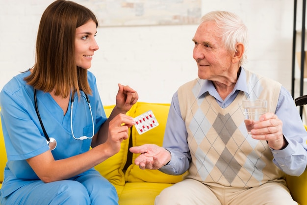 Krankenschwester, die einem alten mann seine pillen gibt