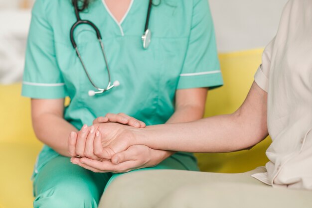 Krankenschwester, die Impuls am Handgelenk des weiblichen Patienten überprüft