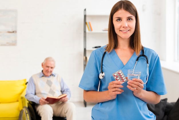 Krankenschwester, die Pillen und Glas Wasser hält