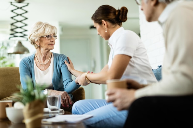 Krankenschwester, die während des Hausbesuchs mit einer älteren Frau kommuniziert. Der Fokus liegt auf der älteren Frau