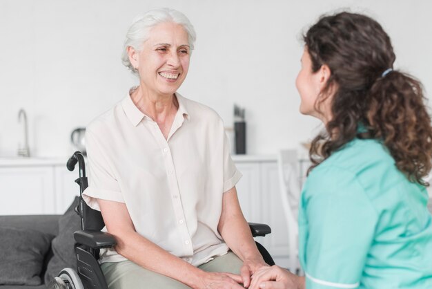 Krankenschwester, die weiblichen älteren Patienten auf Rollstuhl betrachtet