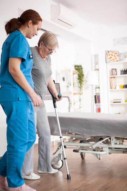 Kostenloses Foto krankenschwester hilft alten frauen mit gehproblemen im pflegeheim mit krücken.