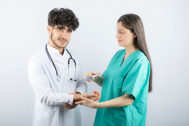 Krankenschwester in grüner Uniform, die dem männlichen Arzt eine Injektion gibt.