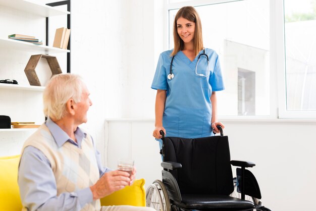 Krankenschwester kommt mit einem Rollstuhl