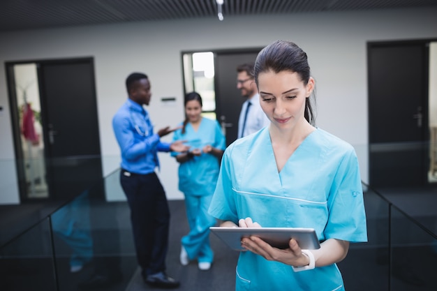 Krankenschwester mit digitaler Tablette im Krankenhauskorridor