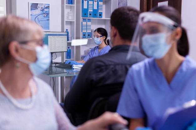 Krankenschwester mit Maske, die am Computer neue Patiententermine tippt