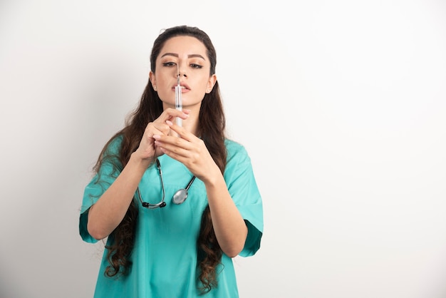 Krankenschwester mit Stethoskop, das eine Spritze in ihren Händen hält.