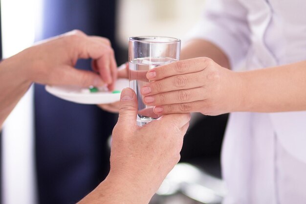 Krankenschwester reicht ihrem Patienten etwas Wasser