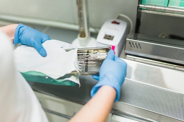 Kostenloses Foto krankenschwesterhand, die zahnmedizinisches instrument in der plastiktasche verpackt