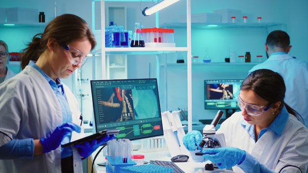 Krankenschwestern, die gemeinsam Virusmutationen analysieren, arbeiten Überstunden in einem mit Chemie ausgestatteten Labor
