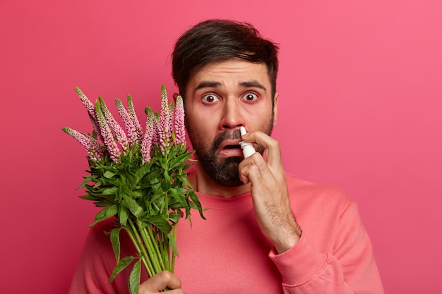 Kranker junger Mann, der an Allergie leidet, isoliert