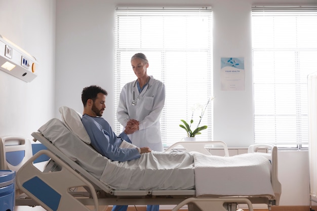 Kranker männlicher Patient im Bett, der mit einer Krankenschwester spricht