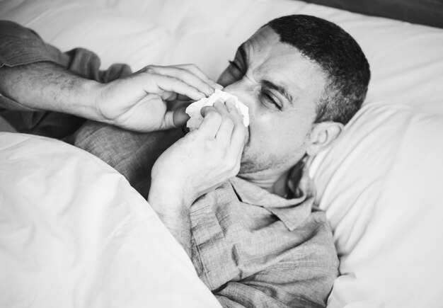 Kranker Mann, der im Bett niest