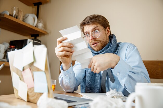 Kranker Mann, der verschreibungspflichtige Medizin liest, die im Büro arbeitet